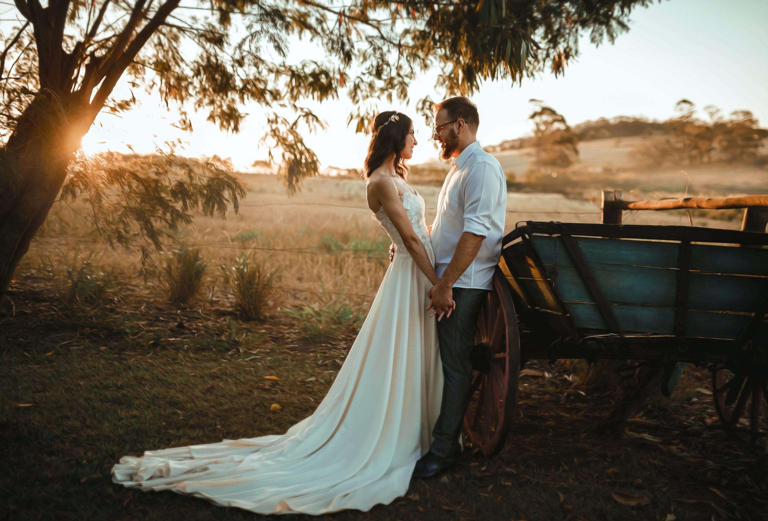 novios recién casados vestidos informales en un campo al atardecer