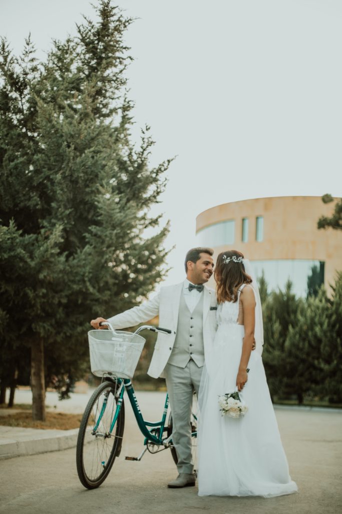 pareja de novios con una bicicleta, mirándose, en una boda de la wedding planner flory ferreras