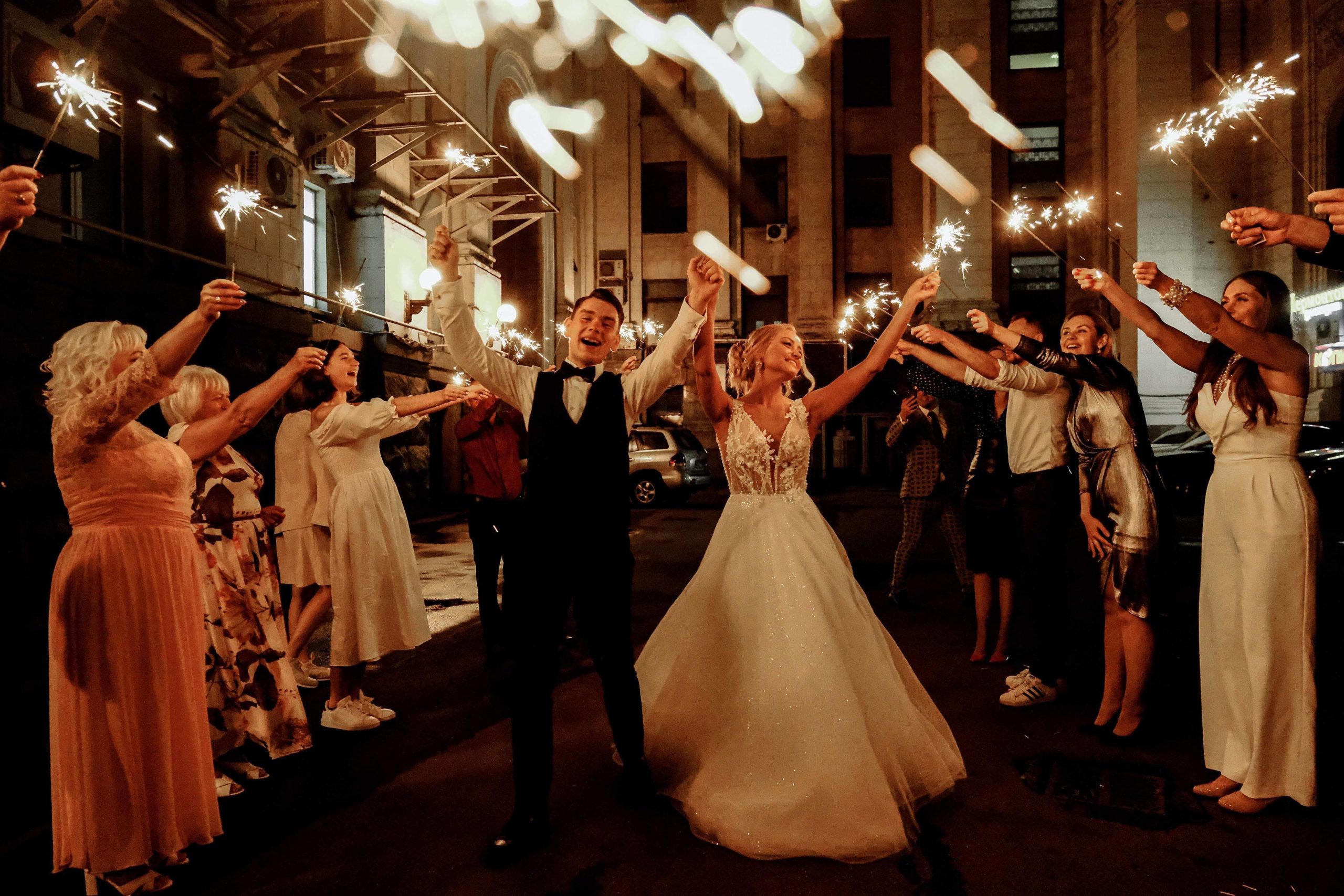 invitados de una boda con palitos luminosos en una boda nocturna alrededor de los novios que están bailando